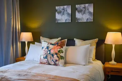 a bedroom with a bed with pillows and two lamps at 1d - Serene Retreat of Parklands in Cape Town