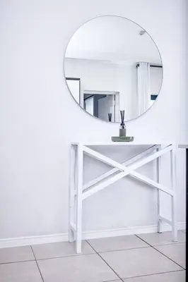 a white table with a mirror on a white wall at 1d - Serene Retreat of Parklands in Cape Town