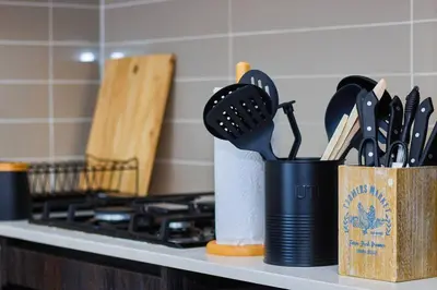 two containers of kitchen utensils on a counter next to a stove at 1d - Serene Retreat of Parklands in Cape Town