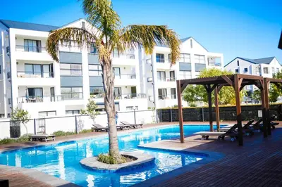 a swimming pool with a palm tree in front of a building at 1d - Serene Retreat of Parklands in Cape Town