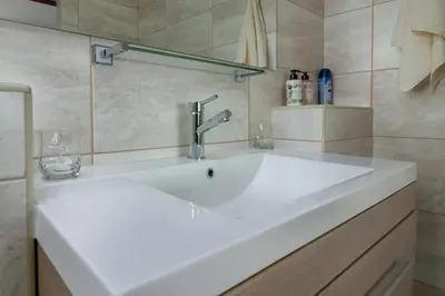 a large white sink in a bathroom with a wall at Le Gaulois Luxury Apartments, sleeps 2, Sea Views in Gordonʼs Bay