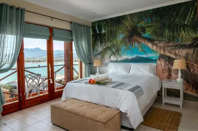 a bedroom with a bed and a palm tree mural at Le Gaulois Luxury Apartments, sleeps 2, Sea Views in Gordonʼs Bay