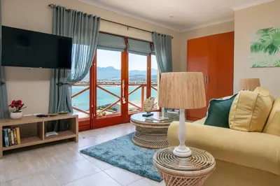 a living room with a couch and a large window at Le Gaulois Luxury Apartments, sleeps 2, Sea Views in Gordonʼs Bay