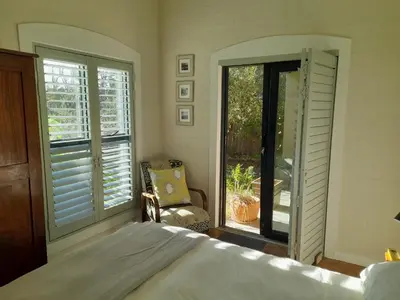 a bedroom with a bed and a window and a chair at Peaceful Seaside Cottage, Betty's Bay Accommodation in Clareport