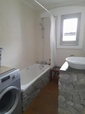 a bathroom with a bath tub and a washing machine at Peaceful Seaside Cottage, Betty's Bay Accommodation in Clareport