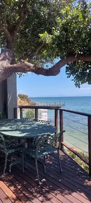 a picnic table on a deck with a view of the ocean at Driftwood Beach Villa in Gordonʼs Bay