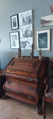 a wooden dresser in a room with pictures on the wall at Driftwood Beach Villa in Gordonʼs Bay