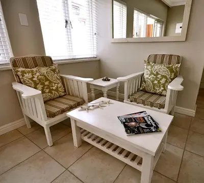 a living room with two chairs and a coffee table at Driftwood Beach Villa in Gordonʼs Bay