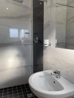 a white bathroom with a sink and a shower at Victoria Lodge Studio Apartment in Cape Town