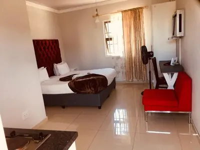 a hotel room with a bed and a red chair at Victoria Lodge Studio Apartment in Cape Town