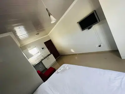 a bedroom with a white bed and a tv at Victoria Lodge Studio Apartment in Cape Town