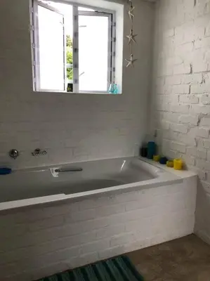 a white bath tub in a bathroom with a window at Rustica in Onrus close to the beach in Hermanus