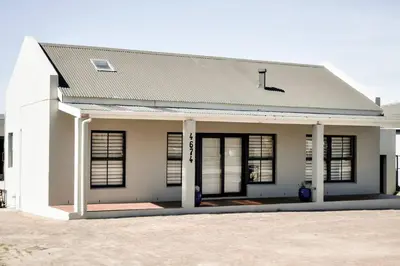 a white building with windows and a roof at Mar-a-Stella Self-Catering Family Retreat in Bettyʼs Bay