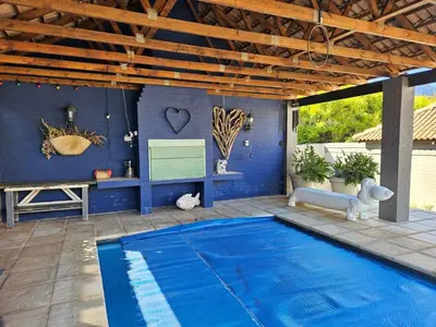 a blue swimming pool in a patio with a wooden ceiling at At 37 Masters Way in Brandwacht