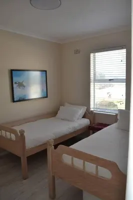 a bedroom with two twin beds and a window at Simplicity with an ocean view 200 in Hermanus