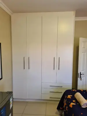 a bedroom with white cabinets and a bed at Pemba's residence in Cape Town