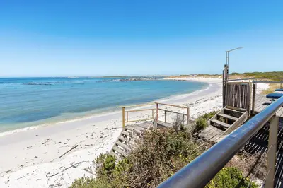a staircase leading down to a beach with the ocean at Hangklip Villa in Pringle Bay