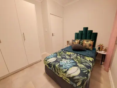 a bedroom with a bed with a green headboard at Serenity on the Atlantic seaboard house shared in Cape Town