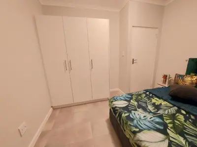 a bedroom with white cabinets and a bed in it at Serenity on the Atlantic seaboard house shared in Cape Town
