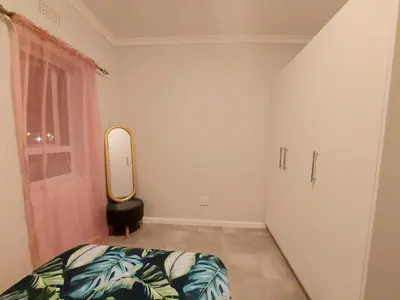 a bedroom with a bed and a mirror at Serenity on the Atlantic seaboard house shared in Cape Town