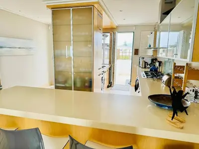 a kitchen with a large counter with chairs in it at 74 on Marine - Apartment 303 in Hermanus