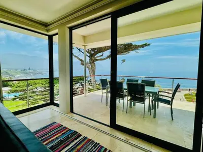 a dining room with a view of the ocean at 74 on Marine - Apartment 303 in Hermanus