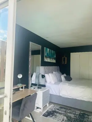 a bedroom with a large bed and a desk and a desk at Tranquil Pool View in Cape Town