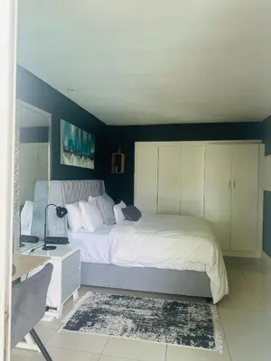 a bedroom with a large white bed and a desk at Tranquil Pool View in Cape Town
