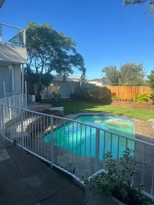 a fence around a swimming pool in a yard at Tranquil Pool View in Cape Town