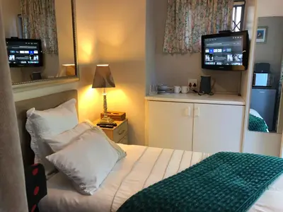 a small bedroom with a bed and a television at Self Catering Guest House in Cape Town