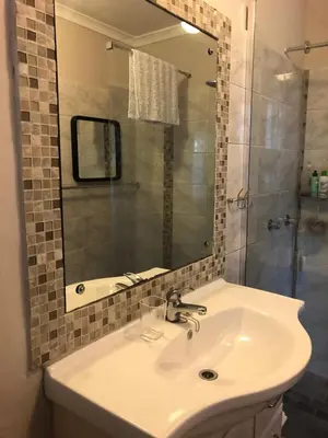a bathroom with a sink and a mirror and a shower at Self Catering Guest House in Cape Town