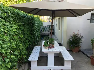 a white bench with an umbrella and potted plants at Self Catering Guest House in Cape Town
