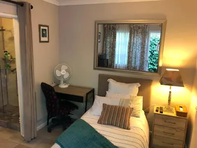 a bedroom with a bed and a desk and a mirror at Self Catering Guest House in Cape Town