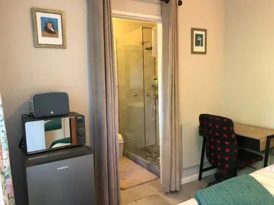 a bathroom with a shower and a television on a table at Self Catering Guest House in Cape Town