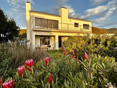 a house with a flower garden in front of it at Happy Place Pringle Bay for 2 in Pringle Bay