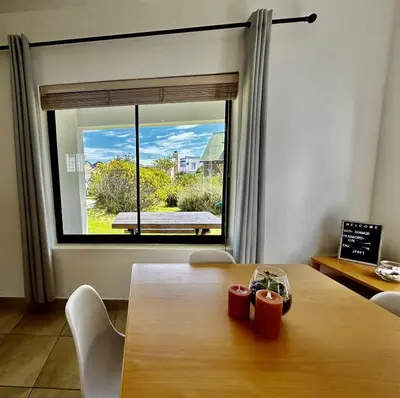 a dining room with a table and a large window at Happy Place Pringle Bay for 2 in Pringle Bay