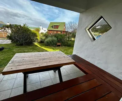 a wooden picnic table on a patio with a window at Happy Place Pringle Bay for 2 in Pringle Bay