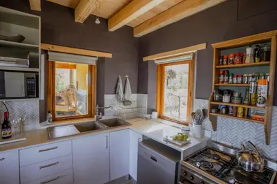 a kitchen with white cabinets and a stove and windows at Berghuis - Mountain Hideaway in Wolseley