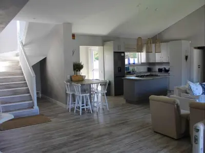 a kitchen and living room with a table and chairs at Nest Egg Holiday Home Voëlklip in Hermanus