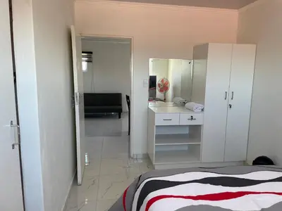a bedroom with a bed and a bathroom with a mirror at The MK House in Cape Town