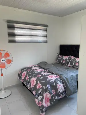 a bedroom with a bed with a floral bedspread and a fan at The MK House in Cape Town