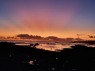 a sunset on the beach with a rainbow in the sky at Belle View Guest Suite in Hermanus