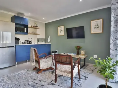 a living room with a table and chairs and a kitchen at Salt Shore Studios in Hermanus