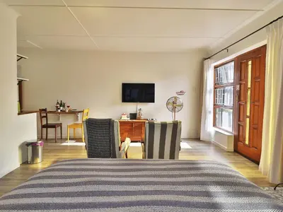 a living room with a bed and a tv at Salt Shore Studios in Hermanus