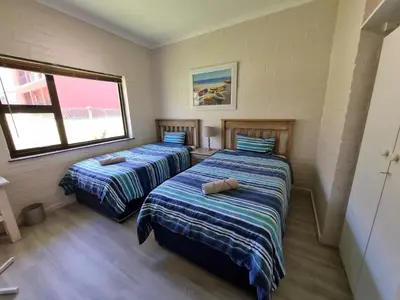 a bedroom with two beds and a window at Milkwood Cottage in Bettyʼs Bay