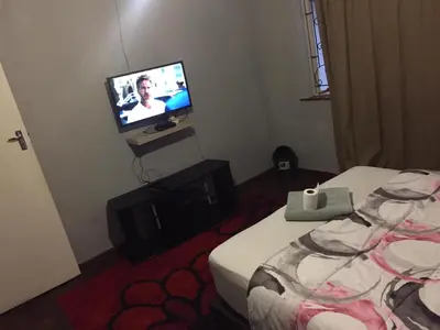 a bedroom with a bed and a tv on the wall at ATHOME BELLVILLE Chrismar in Cape Town