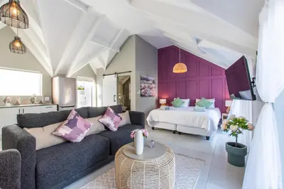 a living room with a couch and a bed at The Fuchsia Collection in Somerset West