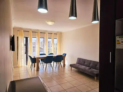 a living room with a table and chairs and a couch at Strand Beach Apartment in Cape Town
