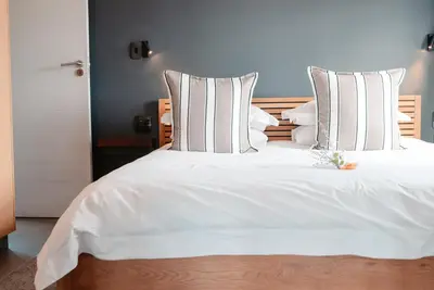 a bed with white sheets and pillows in a room at Khanyisa Mountain Lodge in Robertson