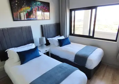 two beds in a hotel room with a window at Cape Town Luxury Stays Knightsbridge Luxury Apartment Century City in Cape Town